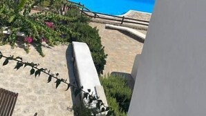 A balcony with a view of a swimming pool and the sea. - Luxury Sea View Apartment w shared pool (Mykonos)