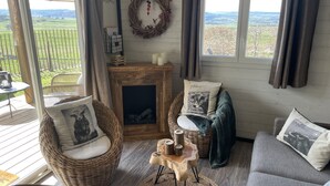 A cozy living room with wicker furniture, a fireplace, and a view of the countryside.