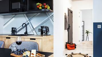 A modern kitchen with a microwave, coffee maker, and a fruit bowl on the counter.