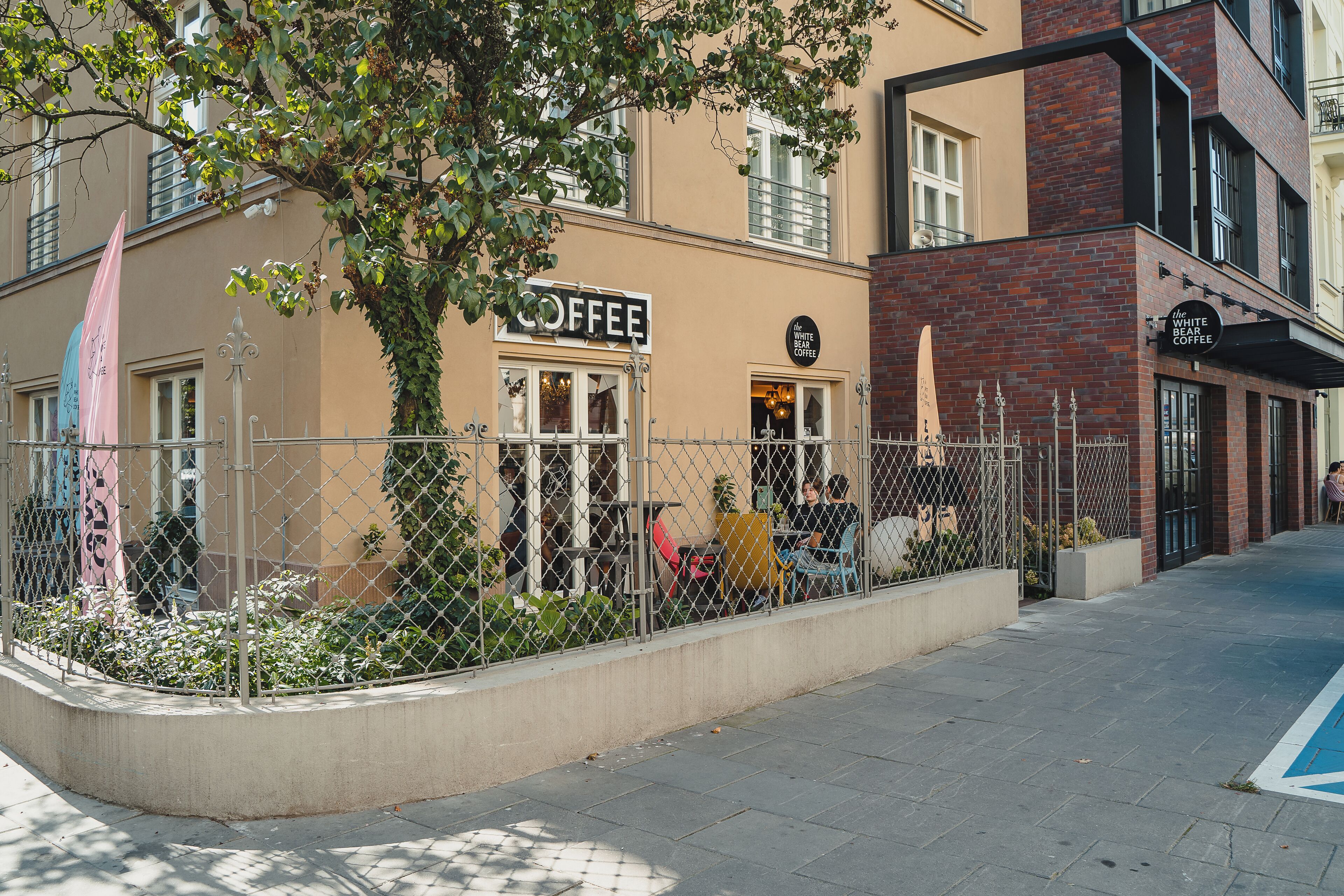 A coffee shop with outdoor seating, a fenced garden area, and a pedestrian pathway.