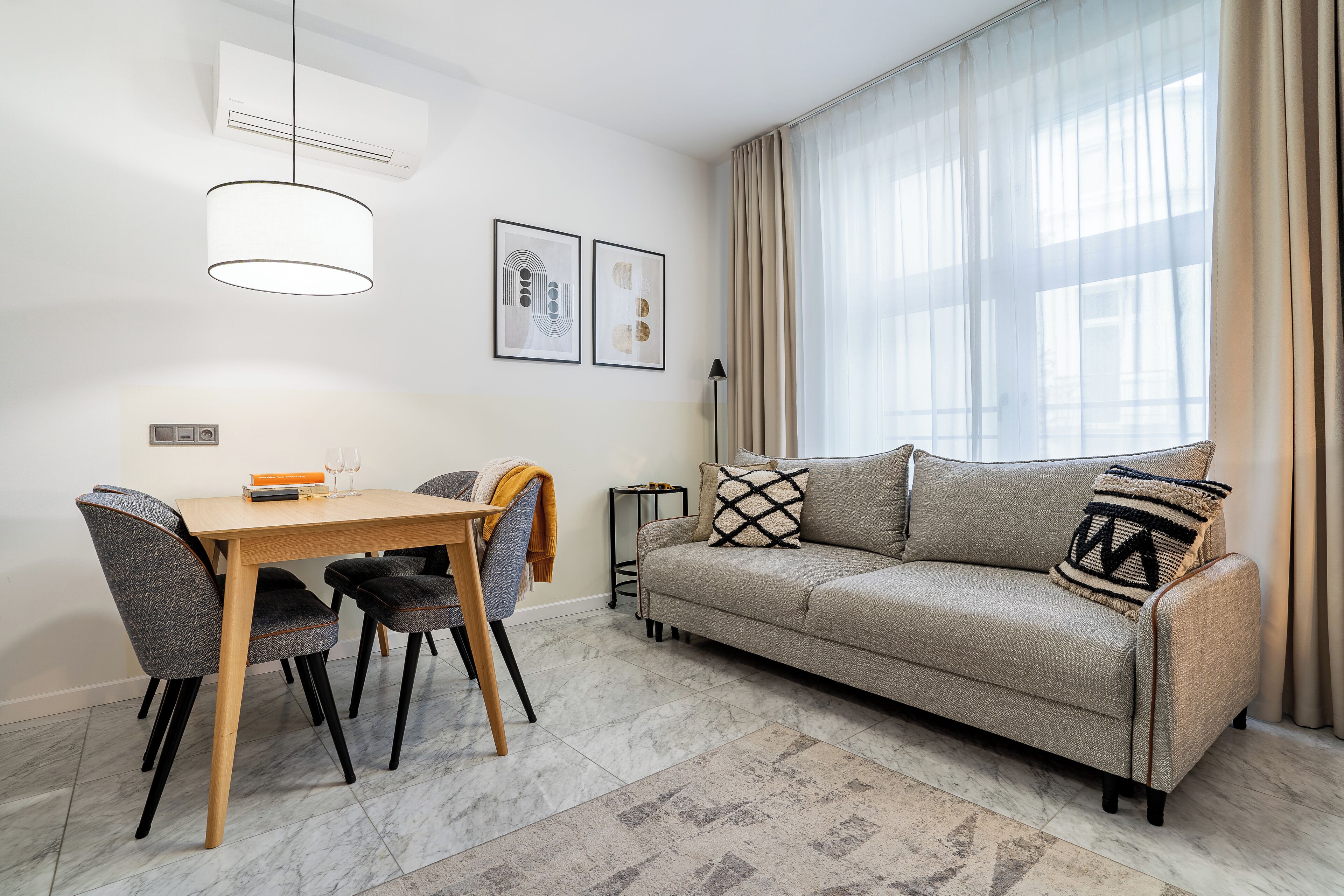 A modern living room with a sofa, a dining table with chairs, and a floor lamp.