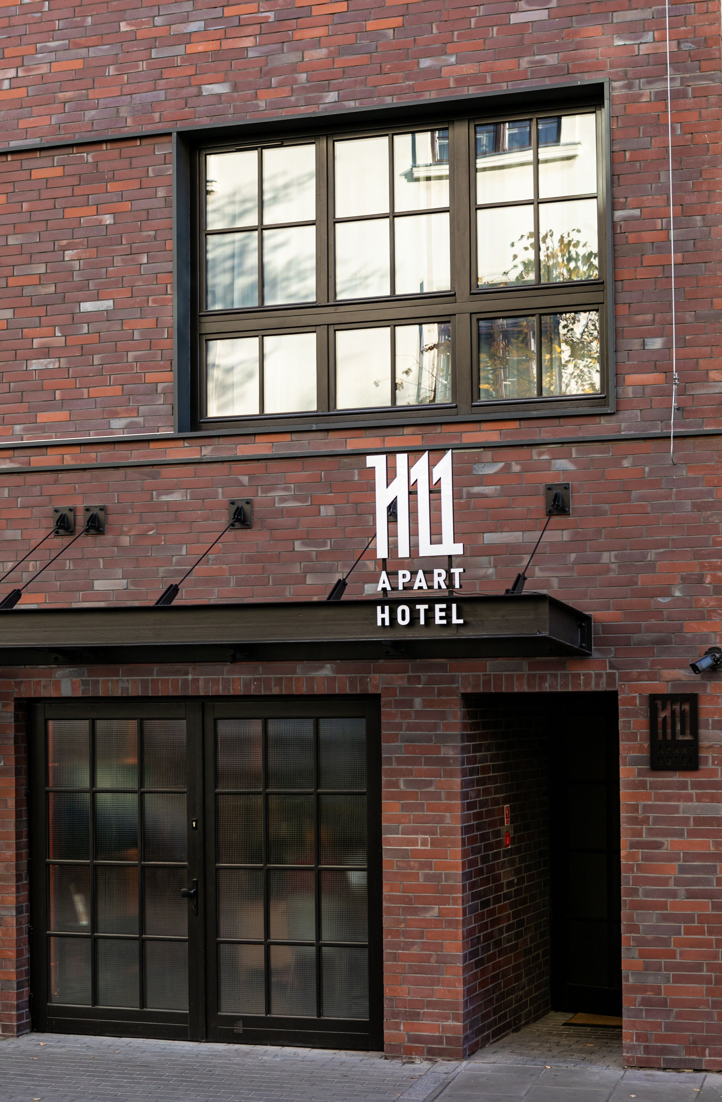 Um edifício de tijolos com uma grande janela e uma placa que diz 'H11 APART HOTEL'.