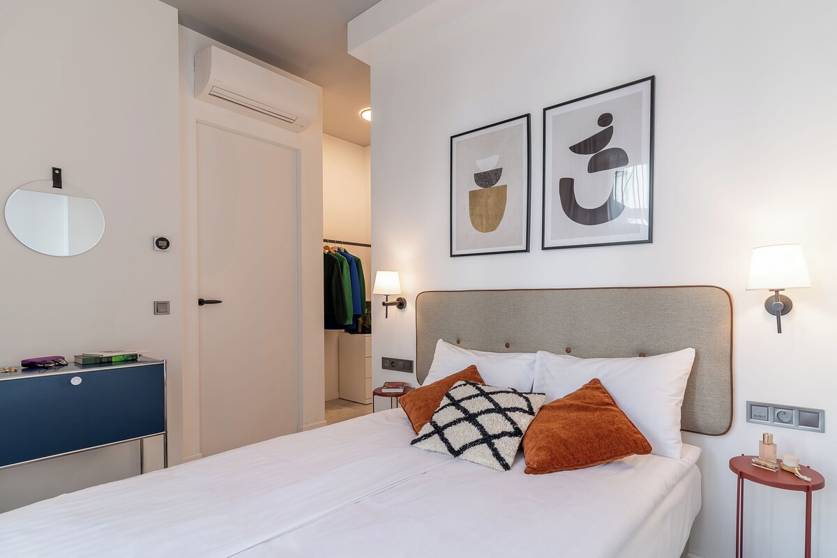 A neatly arranged hotel room with a bed, bedside tables, a wardrobe, and a mirror.