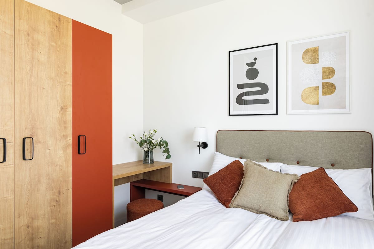 Ein Hotelzimmer mit einem Bett, einem Holzschrank, einem Schreibtisch und einer Wandlampe.