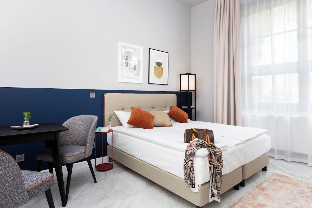 Ein Hotelzimmer mit Bett, Schreibtisch, Stuhl und einem Fenster mit Vorhängen.