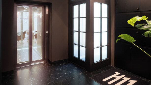 A modern lobby with a glass door entrance, a large window, and a reception desk. - H11 Aparthotel (Kraków)