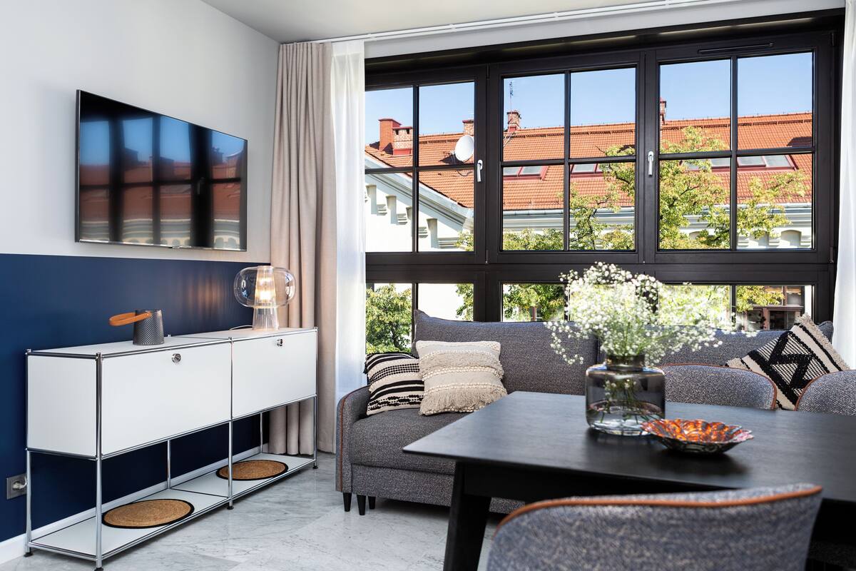 Ein modernes Wohnzimmer mit einer Couch, einem Esstisch und einem an der Wand befestigten Fernseher.