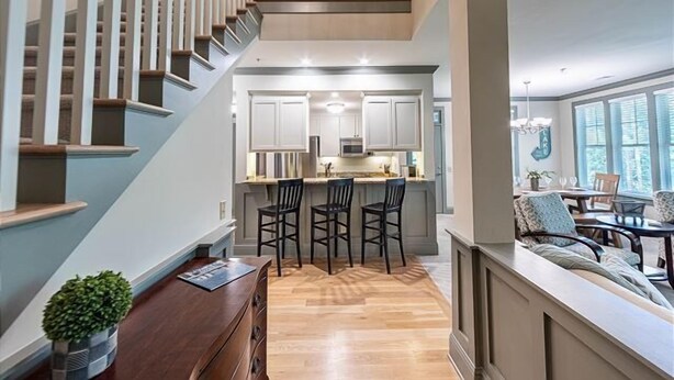 A modern kitchen with a central island, bar stools, and a dining area with a view of the outdoors.