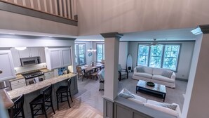 A spacious kitchen with a central island, dining area with a table and chairs, and a living room with a sofa and coffee table.
