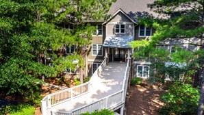 A large two-story house with a covered porch and a wooden deck.