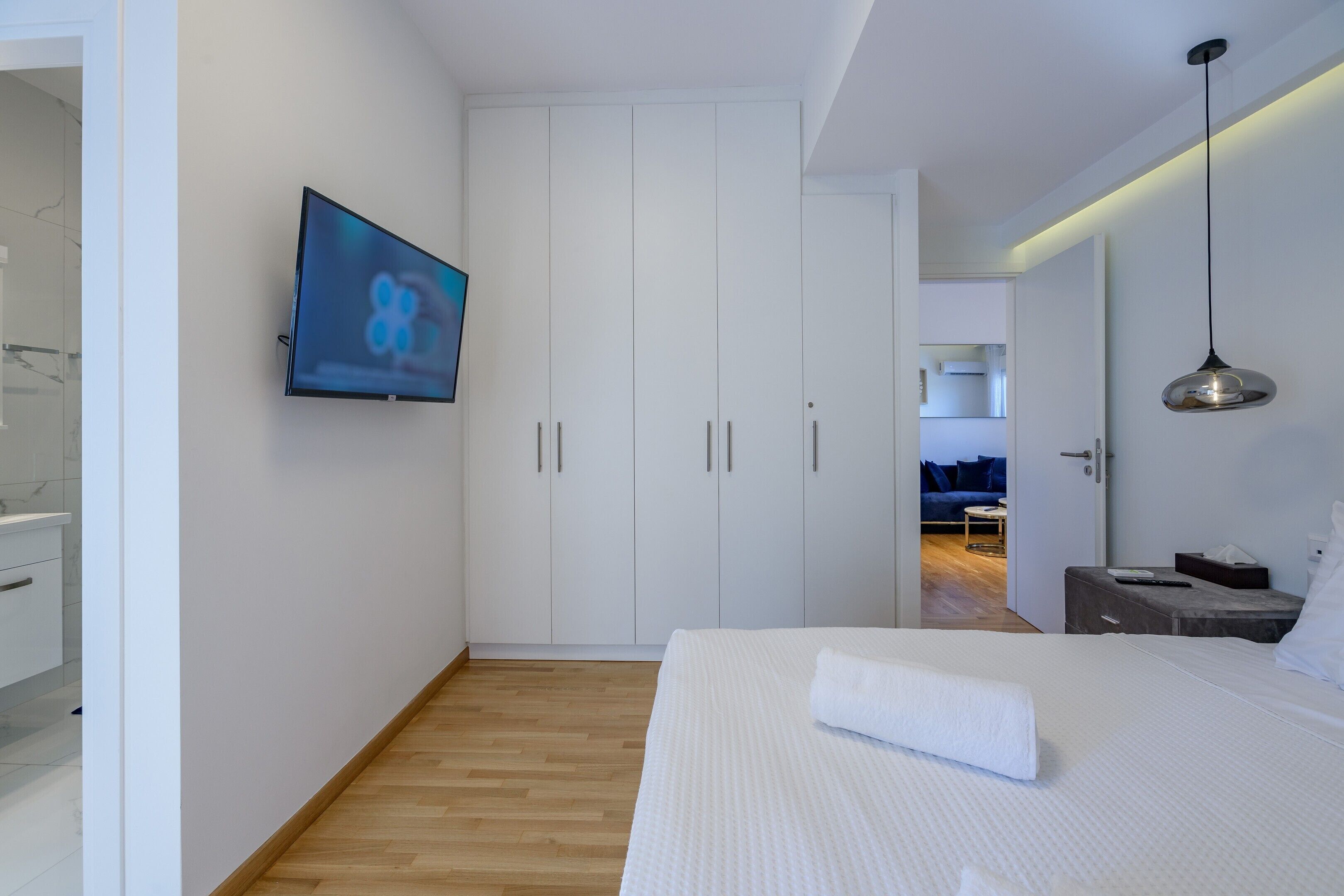 Une chambre à coucher moderne avec un grand lit, un téléviseur fixé au mur et une armoire à portes coulissantes.