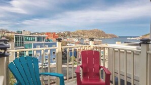 A balcony with two chairs, a view of a coastal town, and a mountain in the distance. - Historic Luxury Downtown Victorian home with Hot Tub, Ocean and Harbour Views (St. John's)