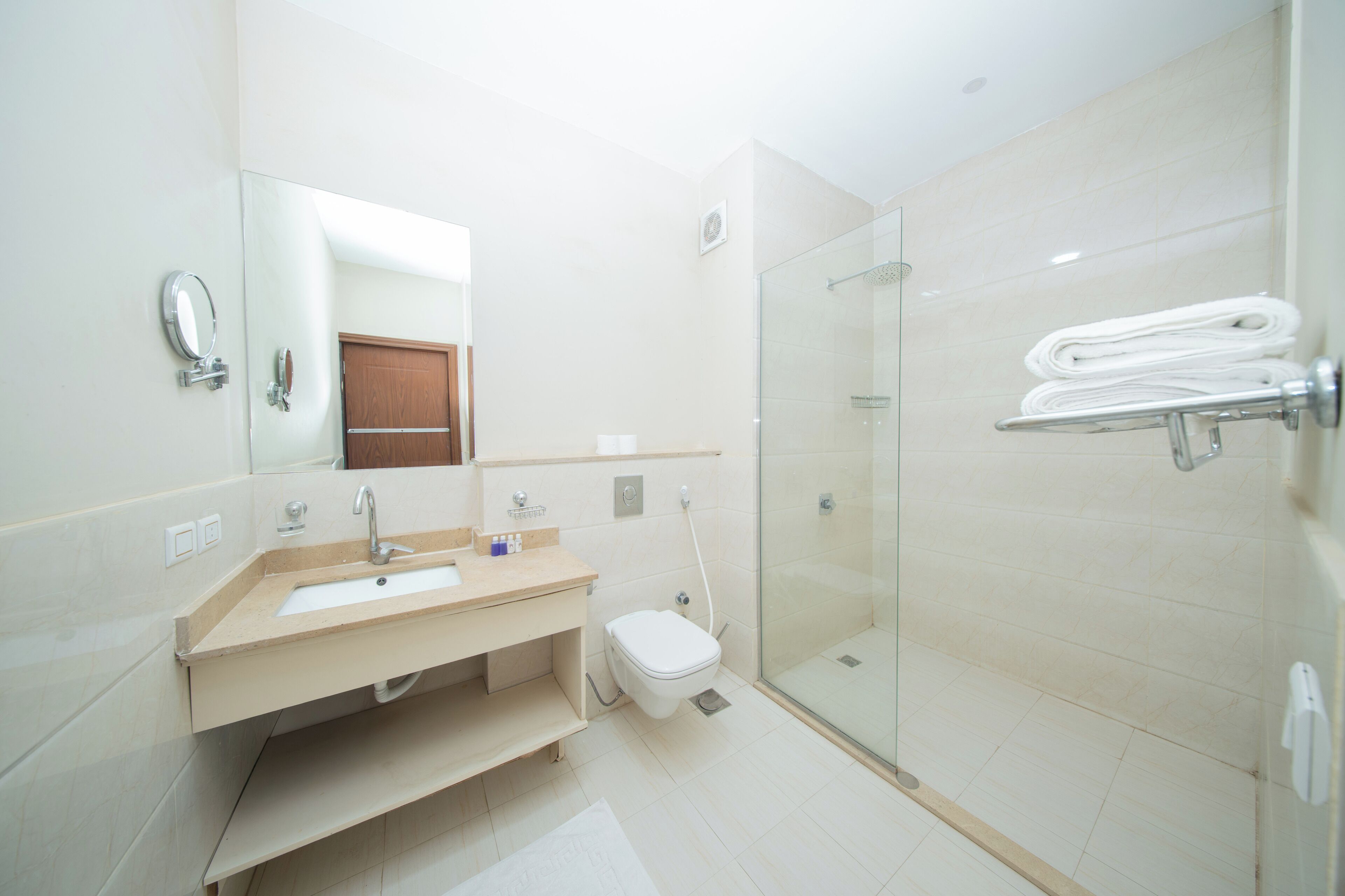 A modern bathroom with a sink, mirror, toilet, and glass shower enclosure.