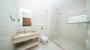 Un baño moderno con lavamanos, espejo, inodoro y cabina de ducha de vidrio.