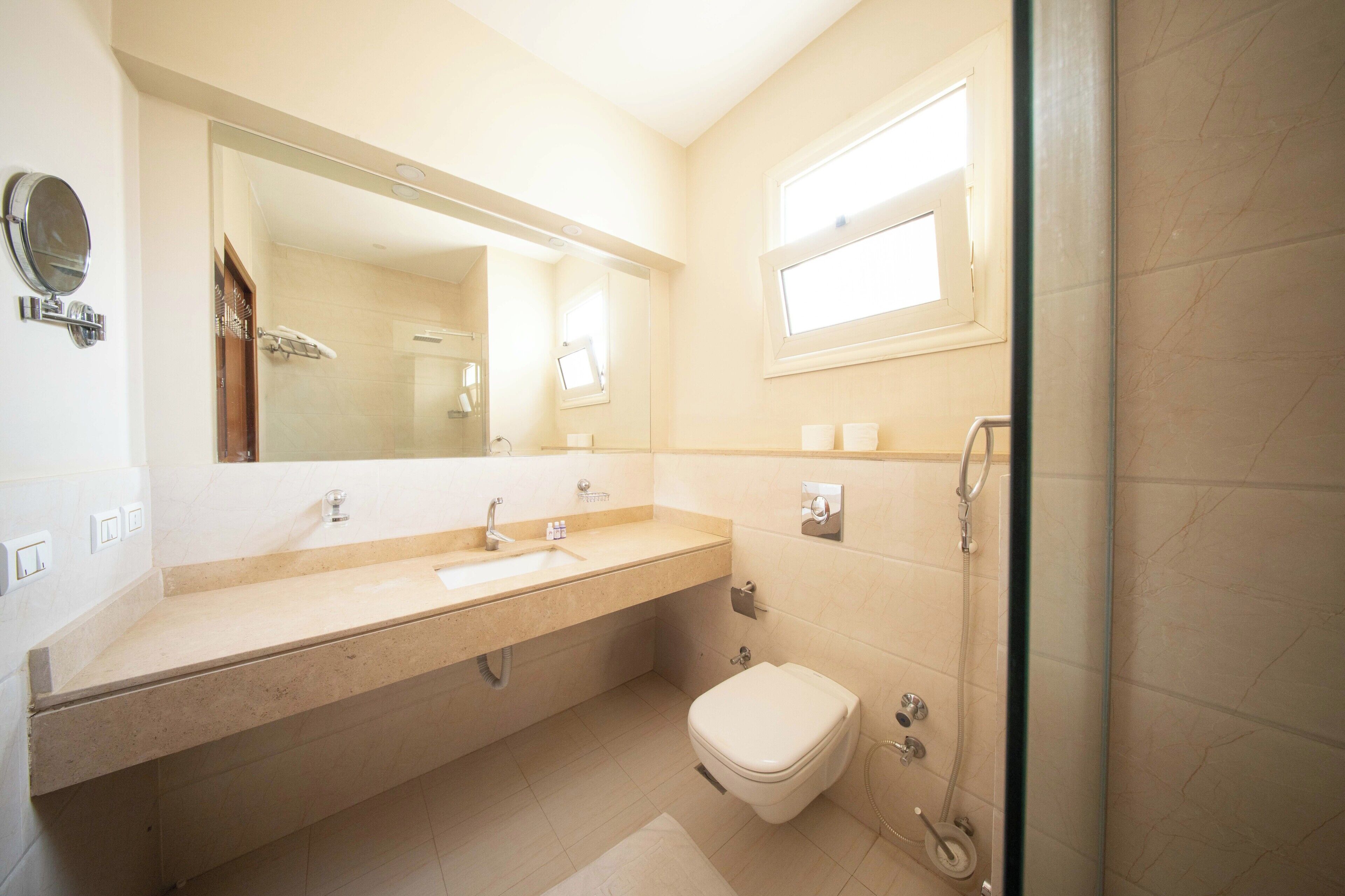 Une salle de bain équipée d’un lavabo, d’un miroir, de toilettes et d’une douche.