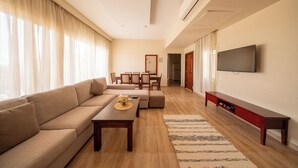 A modern living room with a sofa, coffee table, TV, and a dining area. - The Home (6th of October City)