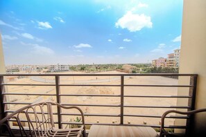 A balcony with a metal railing, a wooden table, and a chair.