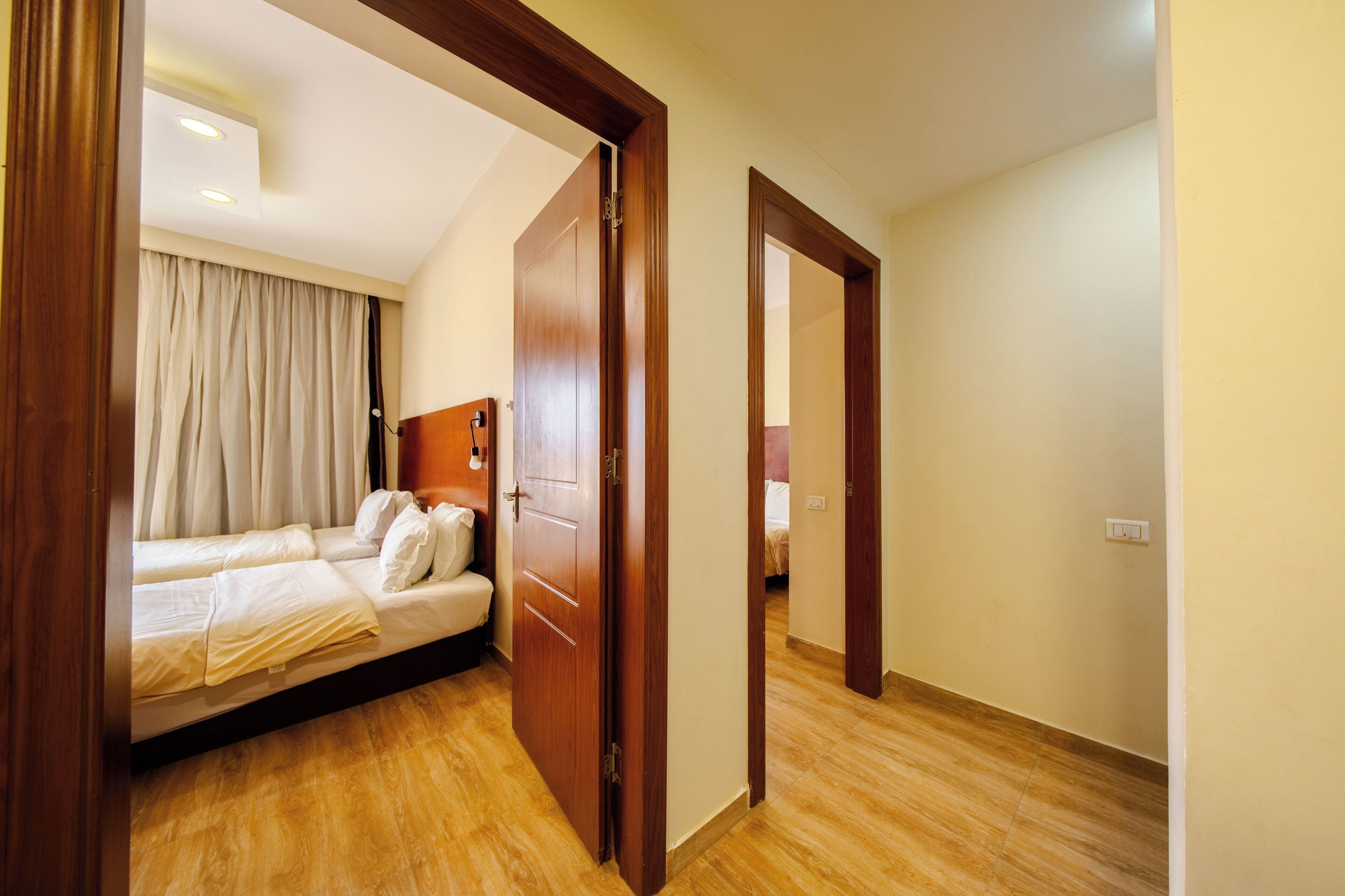 A hotel room with a wooden bed, a wooden door, and a light-colored wall.