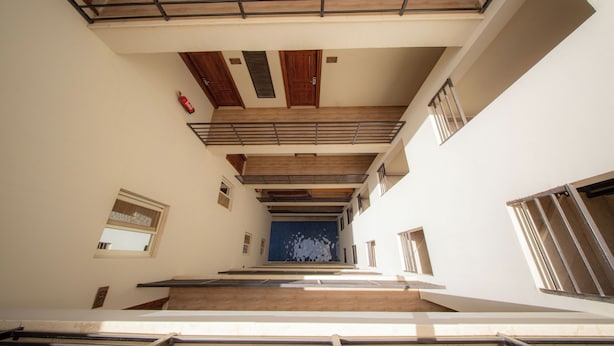 A multi-level interior with a staircase, wooden beams, and a blue wall. - The Home (6th of October City)