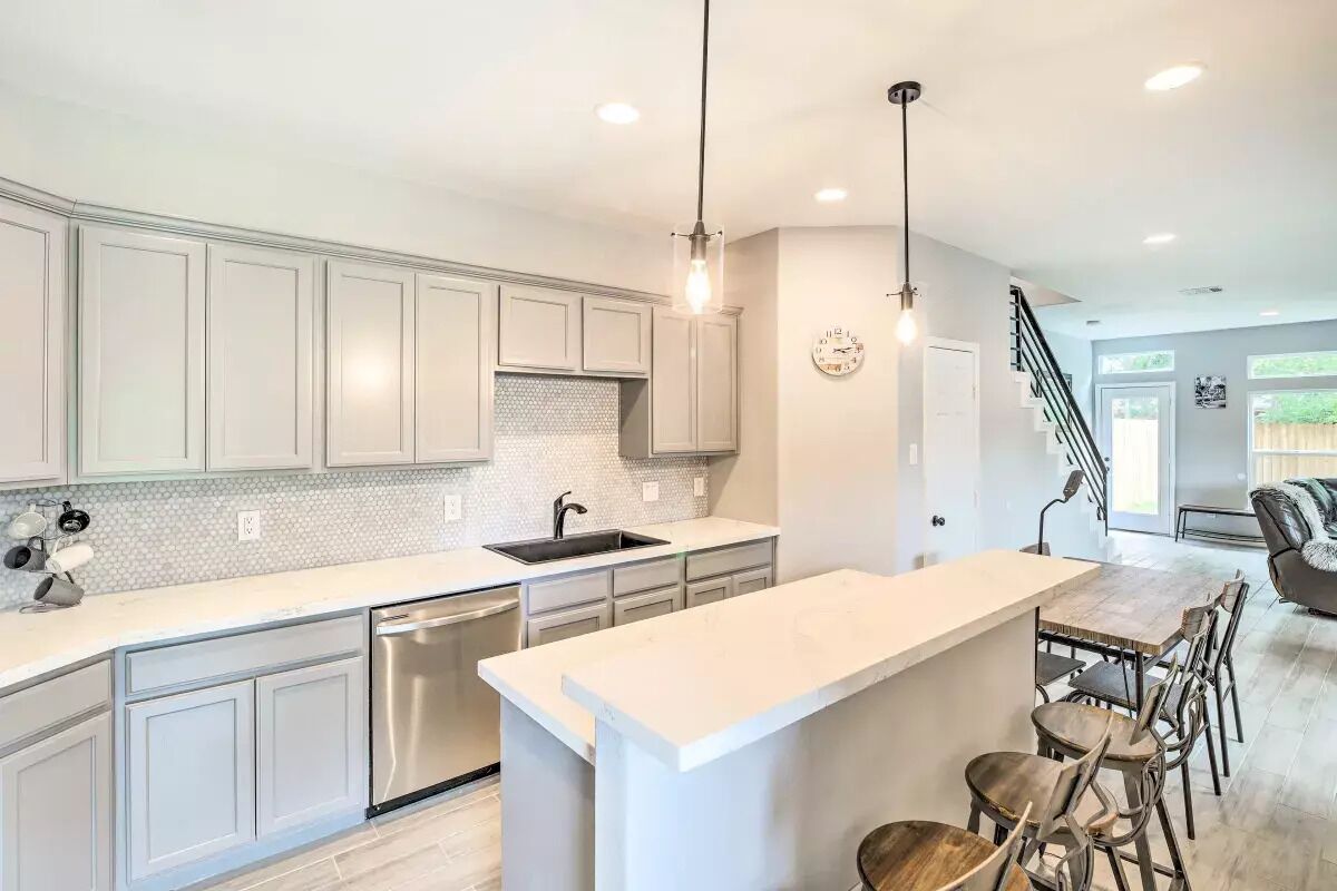 A modern kitchen with white cabinetry, a large island, and pendant lighting.