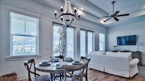 Een moderne woonkamer met een witte bank, een eettafel met stoelen en een kroonluchter.