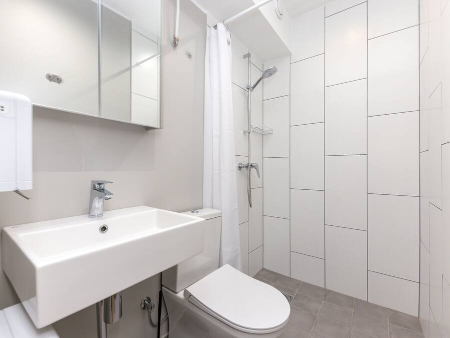 Un baño moderno con lavamanos, inodoro y ducha blancos.
