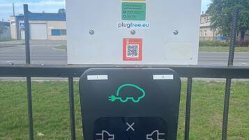 A parking sign with QR codes and a PlugFree charging station.