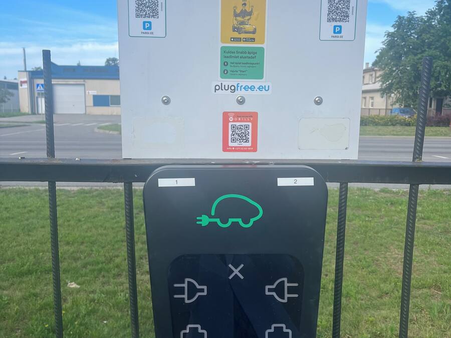 A parking sign with QR codes and a PlugFree charging station.