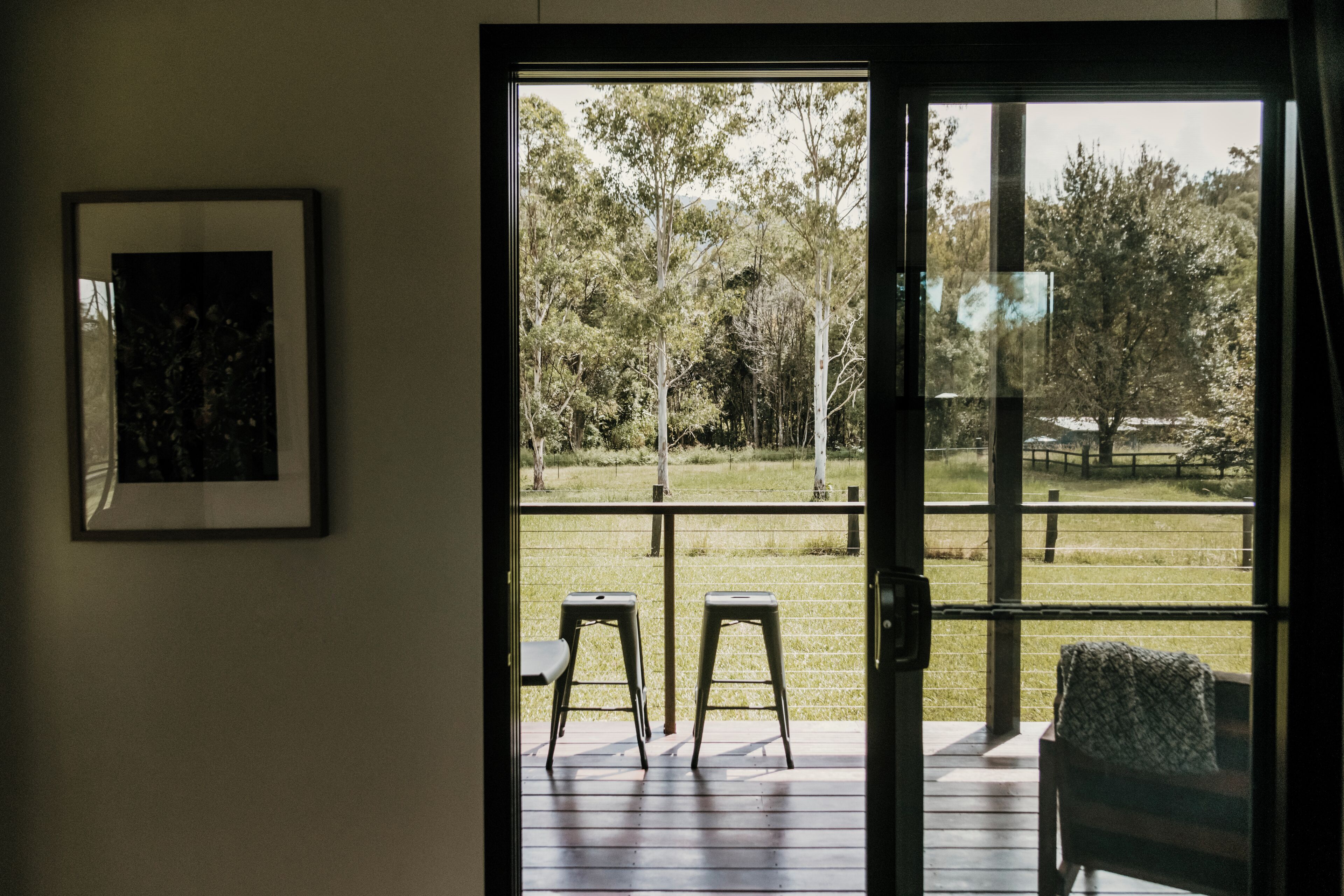 A room with a sliding glass door leading to an outdoor deck with two chairs and a bench.