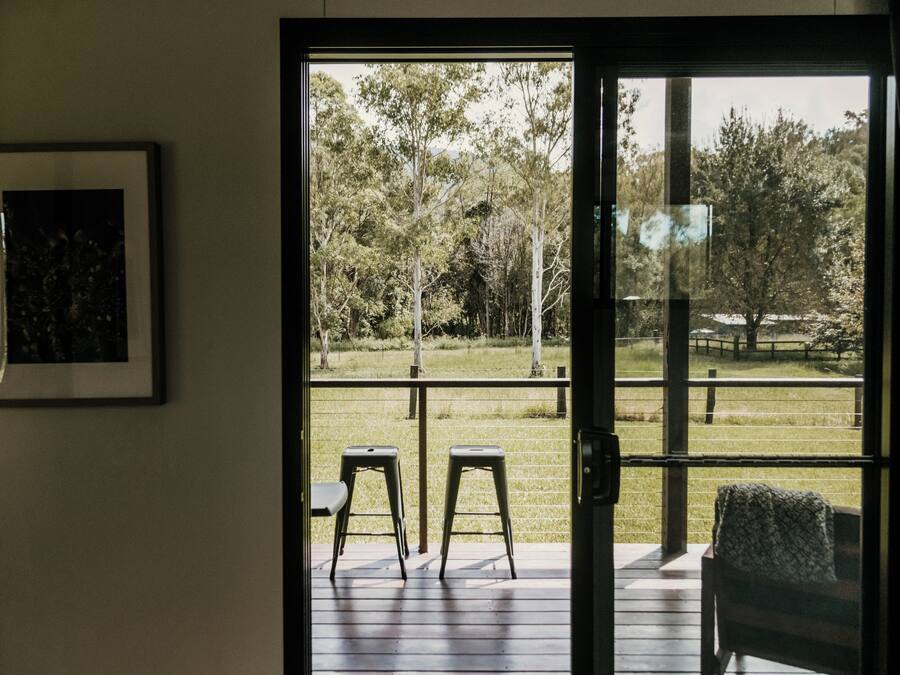 A room with a sliding glass door leading to an outdoor deck with two chairs and a bench.