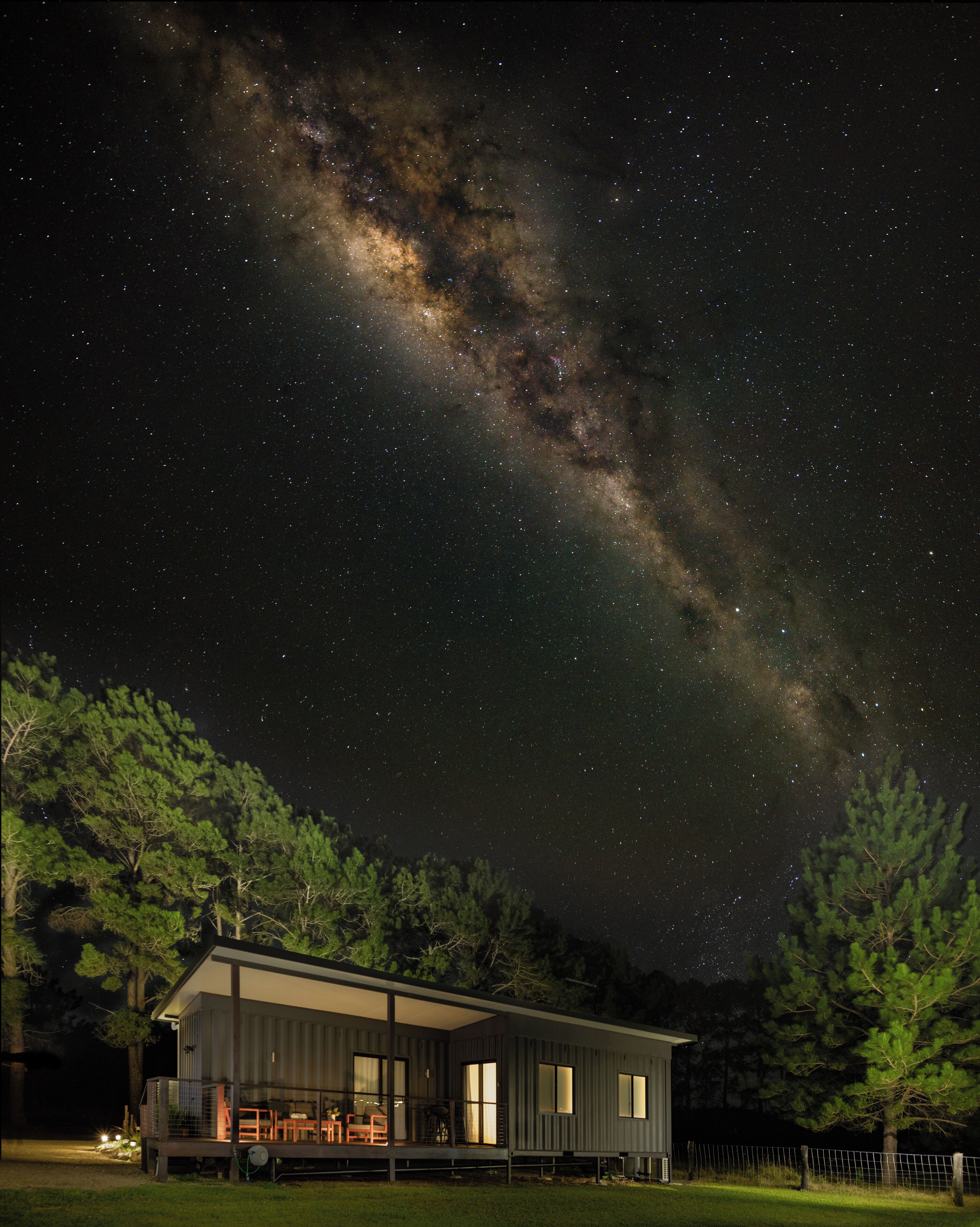 Uma casa moderna com varanda, sob um céu estrelado.