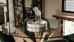 A round glass table with a decorative centerpiece, surrounded by green upholstered chairs. - Contained in Nimbin (Nimbin)