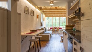 A modern kitchen with wooden cabinets, a dining area with a bench, and a large window providing natural light.