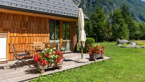 A wooden cabin with a deck, outdoor seating, and flower planters.