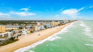 Eine Küstenstadt mit Strand, Gebäuden und blauem Himmel.