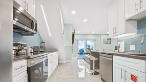 Una cocina moderna con electrodomésticos de acero inoxidable, armarios blancos y un salpicadero de azulejos azules.