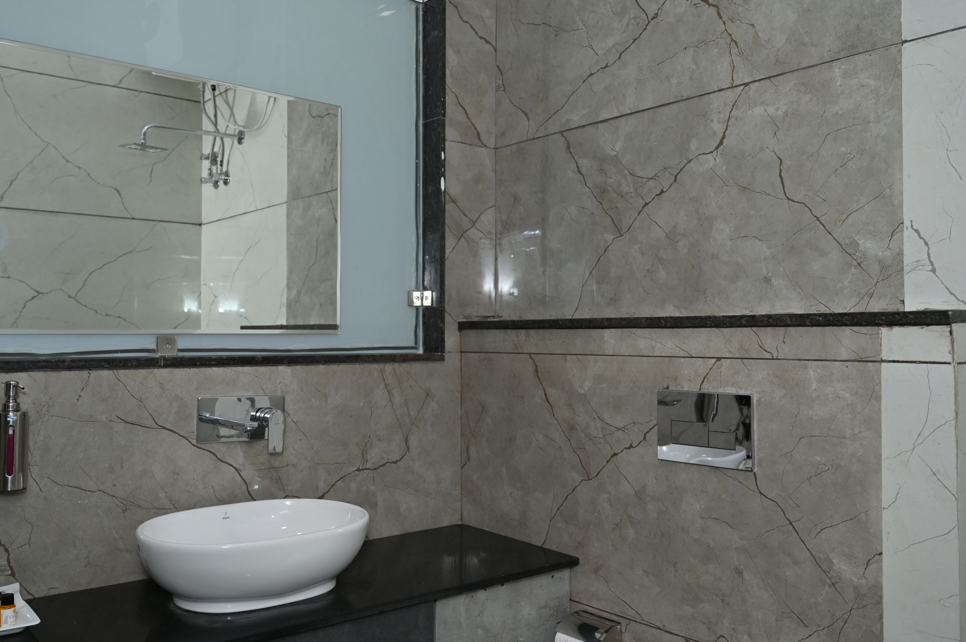 A bathroom with a white sink, a large mirror, and marble walls.