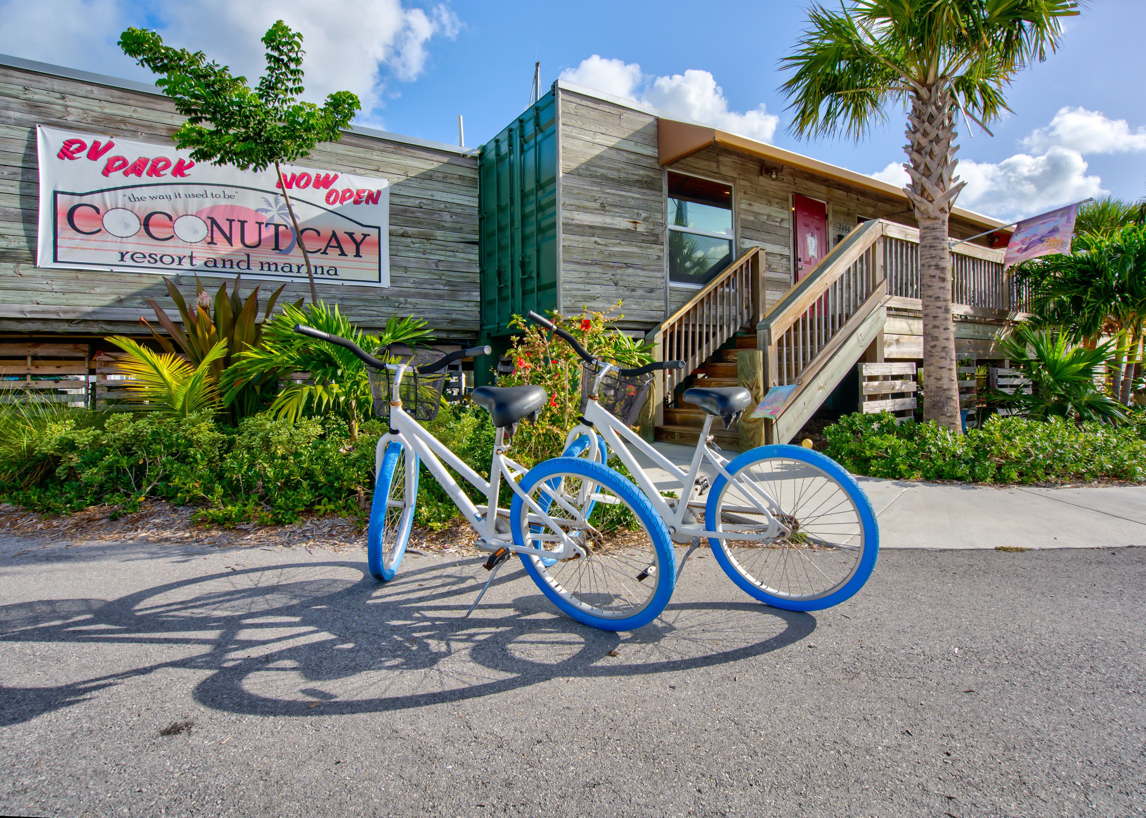 A bicycle parked in front of a building with a sign indicating 'RV Park Now Open' and 'Coconut Cay Resort and Marina'.