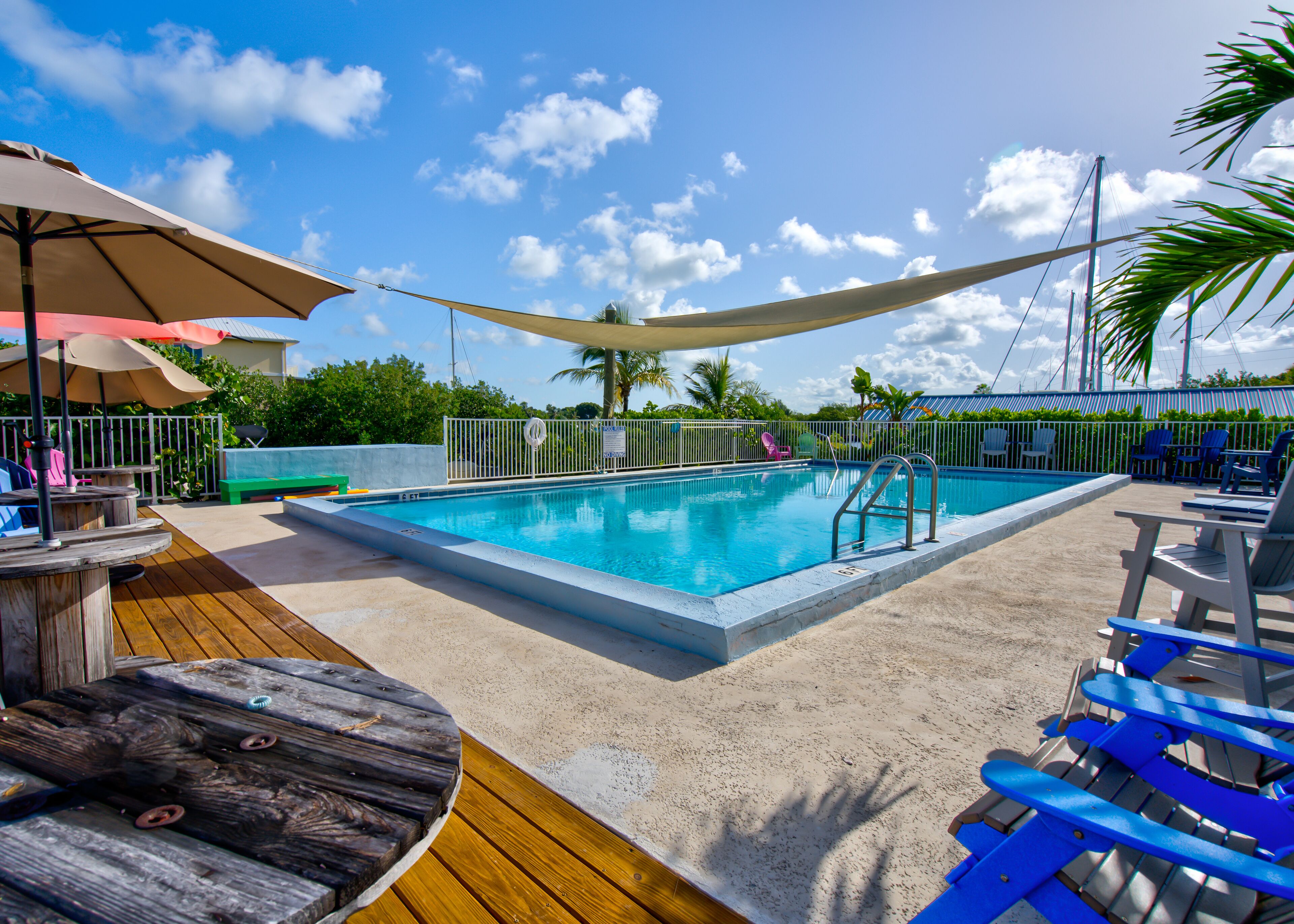 A pool area with a wooden deck, lounge chairs, and umbrellas.