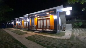 Een modern gebouw met diverse kamers, een overdekt buitengebied en een verzorgd gazon.