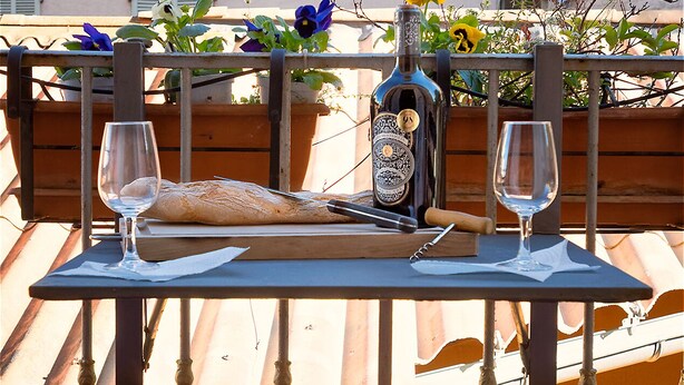 A wooden table with two wine glasses, a bottle, and a loaf of bread. - Adorable 2-bedroom apartment with AC in old town Antibes (Antibes)