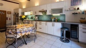 A kitchen with white cabinets, a tiled backsplash, a dining table with chairs, and a bar stool. - Adorable 2-bedroom apartment with AC in old town Antibes (Antibes)