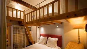 A bedroom with a wooden staircase, a bed with white bedding, a red headboard, a wooden nightstand, and a lamp. - Adorable 2-bedroom apartment with AC in old town Antibes (Antibes)
