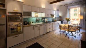 A kitchen with white cabinets, a tiled backsplash, and a dining area with a table and chairs. - Adorable 2-bedroom apartment with AC in old town Antibes (Antibes)