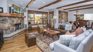 A spacious living room with a stone fireplace, large windows, and a cozy seating area. - Bearpaw D1 4 Bedroom Condo by RedAwning (Avon)