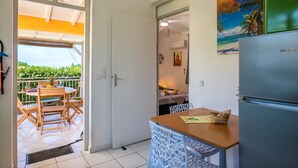 Uma cozinha compacta com geladeira, uma mesa de jantar com cadeiras e vista para a varanda externa.
