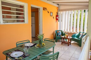Un coin repas avec une table dressée pour deux personnes, un saladier rempli de fruits et un extincteur fixé au mur.