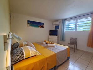 Habitación de hotel con cama, escritorio, silla, ventana con persianas y un cuadro en la pared.
