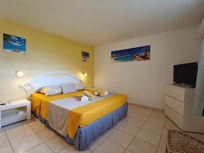A hotel room with a bed, a nightstand, a dresser, and a television.