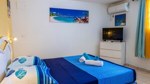 Ein Hotelzimmer mit Bett, Fernseher und einem Bild mit Strandmotiv.